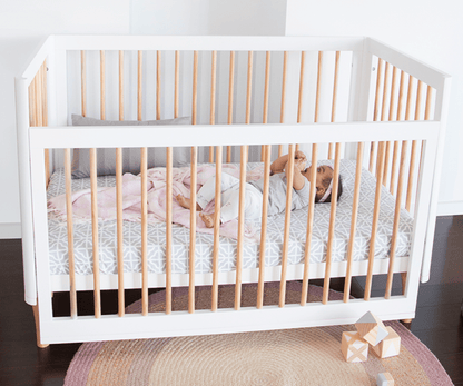 White crib with wooden sides in a room setting