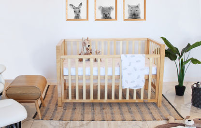 Babyhood Wooden crib in a room with framed animal pictures on the wall.